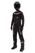 Motocyklista motocrossowy w kompletnym stroju wyścigowym, koszulka 2024 Supertech Ward w kolorze Black Red Berry, czarna koszulka z białym brandingiem Alpinestars, czarne spodnie z czerwonymi panelami bocznymi i dużymi białymi logotypami Astars, czarny kask, rękawice i buty, profesjonalny zestaw do wyścigów off-road