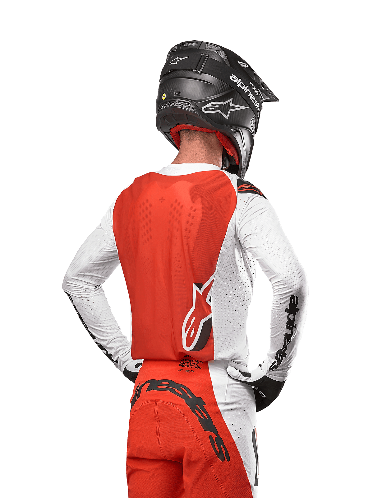 Kierowca motocrossowy w koszulce 2024 Supertech Ward Jersey w kolorze White Hot Orange, widok z tyłu ukazujący pomarańczowy panel tylny i białe rękawy z czarnym brandingiem Alpinestars, w zestawie z dopasowanymi spodniami i czarnym kaskiem, profesjonalny sprzęt do wyścigów terenowych