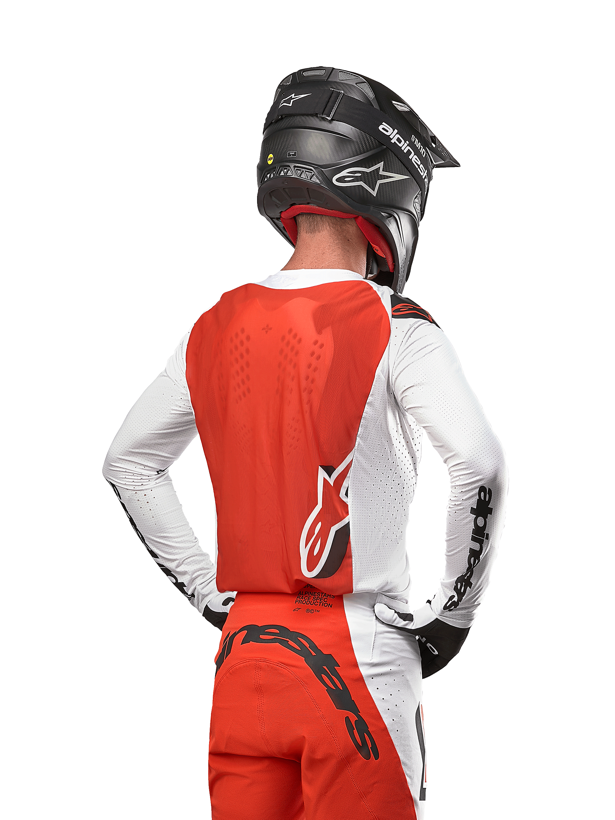Kierowca motocrossowy w koszulce 2024 Supertech Ward Jersey w kolorze White Hot Orange, widok z tyłu ukazujący pomarańczowy panel tylny i białe rękawy z czarnym brandingiem Alpinestars, w zestawie z dopasowanymi spodniami i czarnym kaskiem, profesjonalny sprzęt do wyścigów terenowych