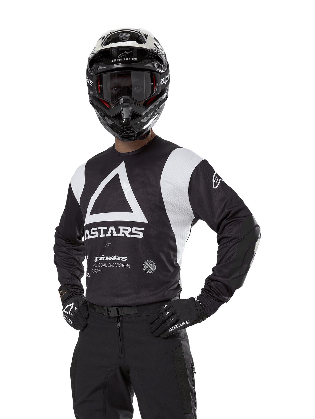 Alpinestars Techdura Jersey, koszulka motocrossowa, czarno-biała, noszona z pasującym kaskiem i rękawicami, poza z rękami na biodrach na białym tle, z dużym trójkątnym logo A i brandingiem ASTARS