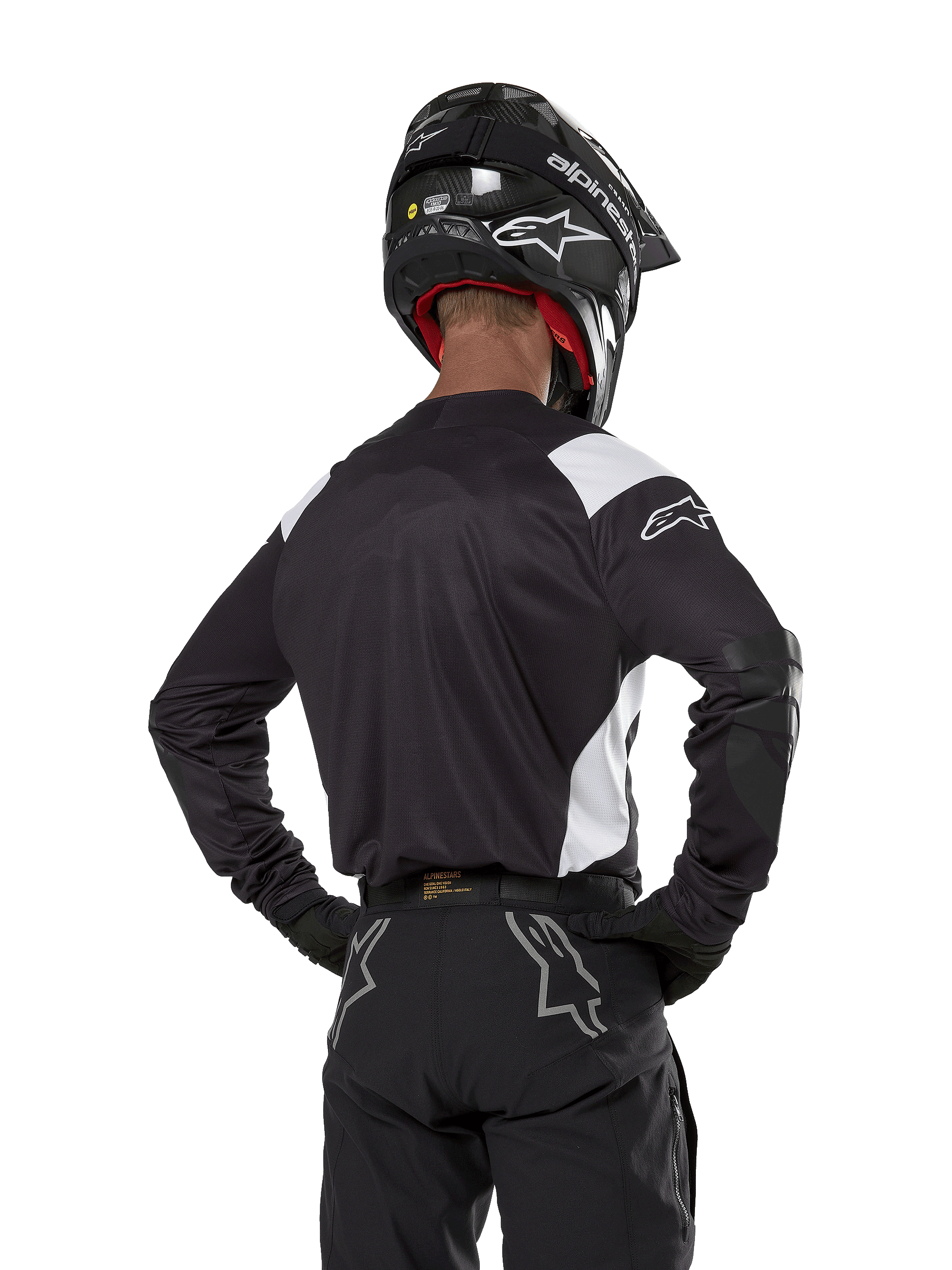 Alpinestars Techdura Jersey, czarna z białymi akcentami na ramionach, widok z tyłu na motocyklistę w pasujących czarnych spodniach i kasku, wzmocnione łaty na łokciach, odzież do enduro i jazdy terenowej