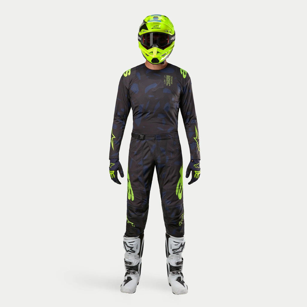 Kierowca motocrossowy w pełnym stroju wyścigowym, koszulka Techstar Rantera 2024 w kolorze Black Navy i Yellow Fluo, dopasowane spodnie z abstrakcyjnym nadrukiem, jaskrawy kask w kolorze żółty fluo, biało-czarne buty, skoordynowany zestaw do wyścigów terenowych