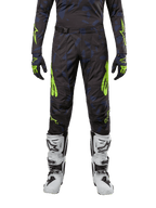 Alpinestars Techstar Rantera Pants 2024, spodnie motocrossowe, czarno-granatowe z jaskrawym żółtym (Yellow Fluo), noszone z pasującą koszulką z długim rękawem, rękawicami i białymi butami motocrossowymi, z wyraźnymi neonowożółtymi akcentami i abstrakcyjnym ciemnym wzorem.