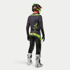 Alpinestars 2024 Techstar Rantera Jersey, koszulka motocrossowa, czarna, granatowa i żółta neonowa, noszona z pasującymi spodniami, biało-czarnymi butami i żółtym neonowym kaskiem, widok z tyłu w pełnym stroju do wyścigów terenowych