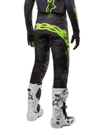 Alpinestars Techstar Rantera Pants 2024, spodnie motocrossowe, czarne, granatowe i neonowo-żółte, widok z tyłu, wyraziste neonowe logo i siatkowe panele wentylacyjne, noszone z pasującą bluzą i białymi butami, wytrzymały sprzęt do motocrossu i wyścigów off-road