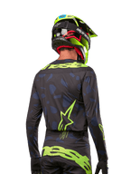 Widok z tyłu zawodnika motocrossowego w koszulce Alpinestars Techstar Rantera 2024 w kolorze Black Navy Yellow Fluo, z wyraźnym neonowo-żółtym brandingiem i logo na plecach, w zestawie z pasującymi spodniami motocrossowymi i neonowo-żółtym kaskiem, tworzącymi kompletny wyścigowy wygląd off-road.