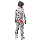 Motocyklista motocrossowy widoczny od tyłu w koszulce Alpinestars 2024 Techstar Rantera i pasujących spodniach, wzór Haze Gray Camo z wyraźnymi czerwonymi logo Alpinestars, czarny kask, biało-czarne buty, czarne rękawice, dopasowany komplet odzieży motocrossowej