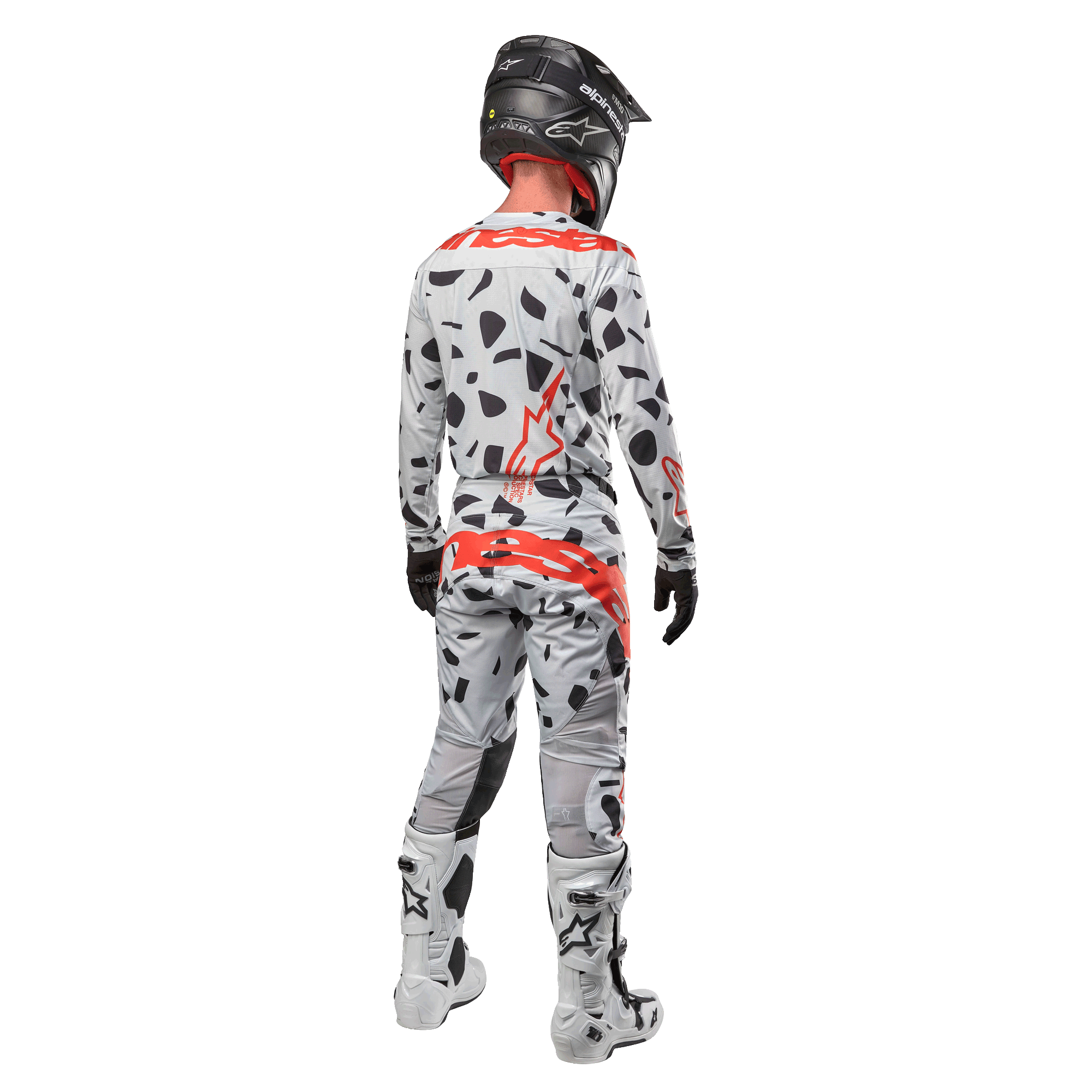 Motocyklista motocrossowy widoczny od tyłu w koszulce Alpinestars 2024 Techstar Rantera i pasujących spodniach, wzór Haze Gray Camo z wyraźnymi czerwonymi logo Alpinestars, czarny kask, biało-czarne buty, czarne rękawice, dopasowany komplet odzieży motocrossowej