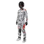 Zawodnik motocrossowy w koszulce Alpinestars 2024 Techstar Rantera w kolorze Haze Gray Camo, pasujące spodnie z czerwonymi i czarnymi akcentami, czarny kask i gogle, czarne rękawice, biało-czarne buty, kompletny, skoordynowany zestaw wyścigowy motocross do jazdy terenowej