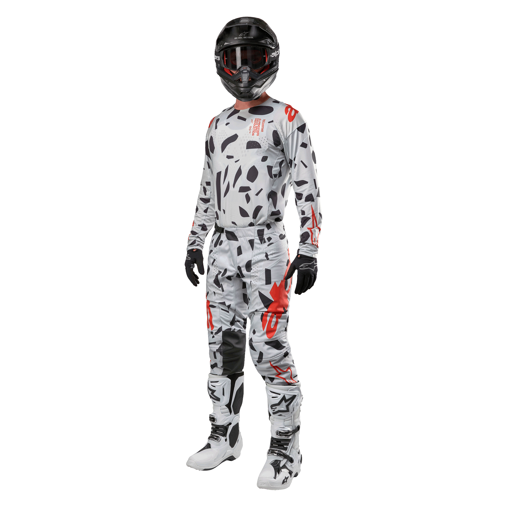 Zawodnik motocrossowy w koszulce Alpinestars 2024 Techstar Rantera w kolorze Haze Gray Camo, pasujące spodnie z czerwonymi i czarnymi akcentami, czarny kask i gogle, czarne rękawice, biało-czarne buty, kompletny, skoordynowany zestaw wyścigowy motocross do jazdy terenowej