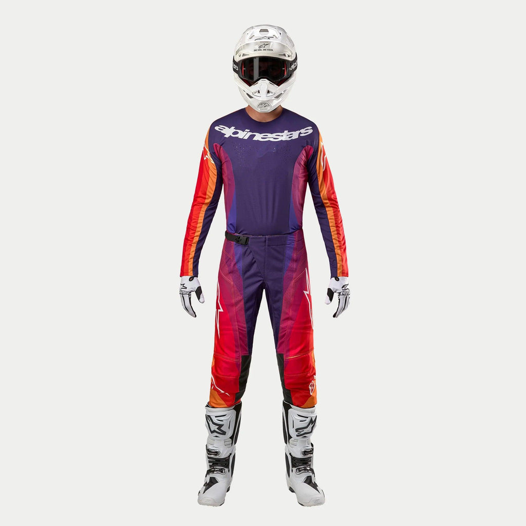 Alpinestars Techstar Pneuma 2024, kompletny strój motocrossowy, fioletowy z pomarańczowymi i niebieskimi akcentami, biały kask, białe rękawice i buty, profesjonalny zestaw wyścigowy