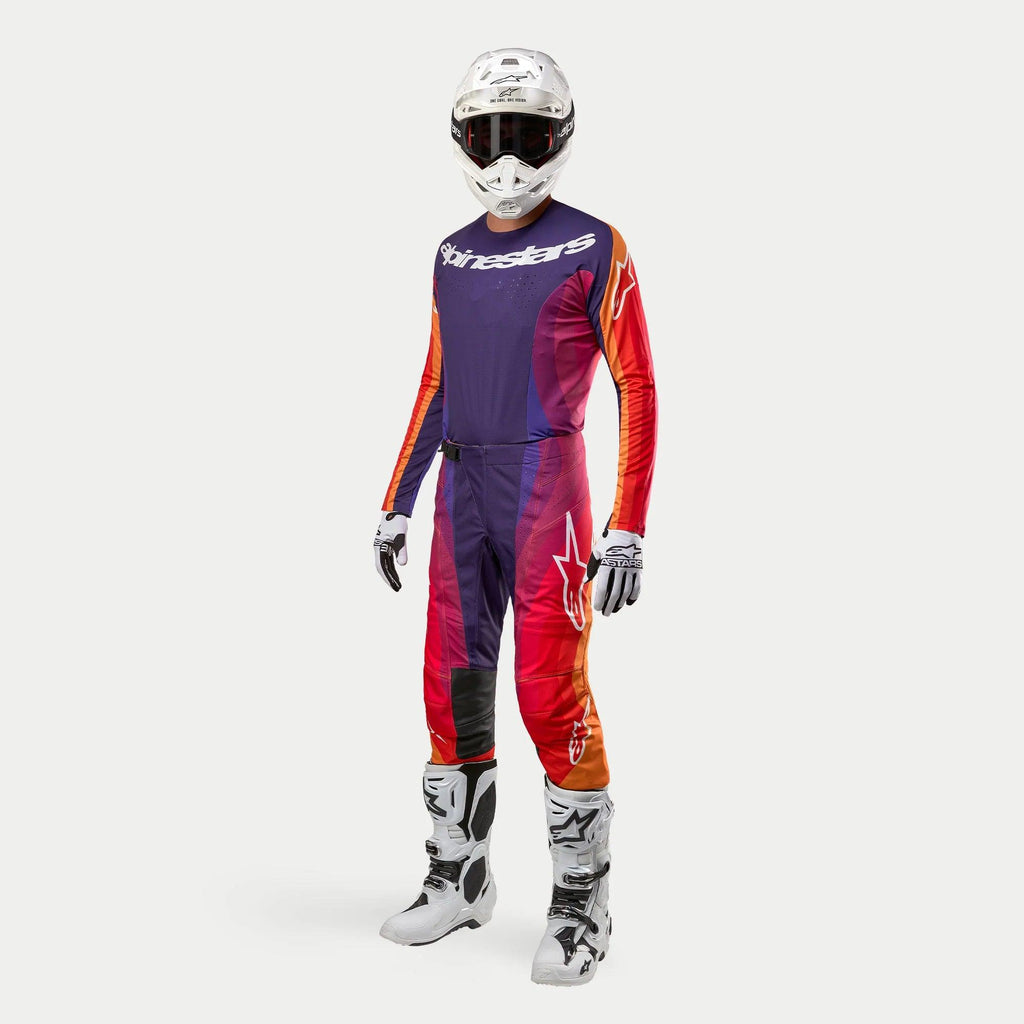 Strój motocrossowy Alpinestars Techstar Pneuma, kompletny zestaw wyścigowy, biały kask, koszulka i spodnie z fioletowym, pomarańczowym i czerwonym gradientem, biało-czarne rękawice, białe buty z czarnymi detalami, logo Alpinestars