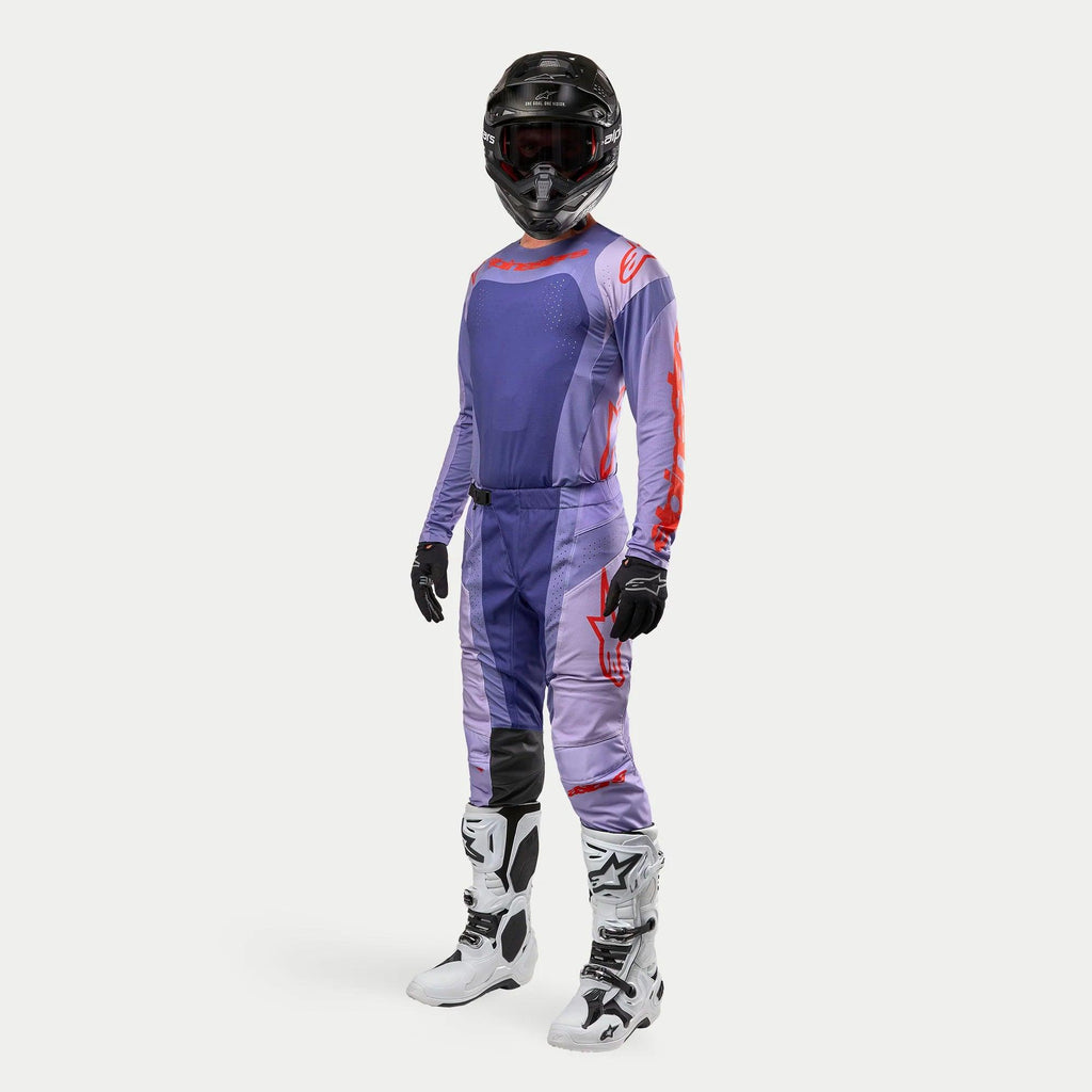Strój motocrossowy Alpinestars, kompletny zestaw wyścigowy Techstar Ocuri 2024, fioletowa koszulka i spodnie z intensywnie pomarańczowymi grafikami, czarny kask, czarne rękawice, białe buty z czarnymi detalami