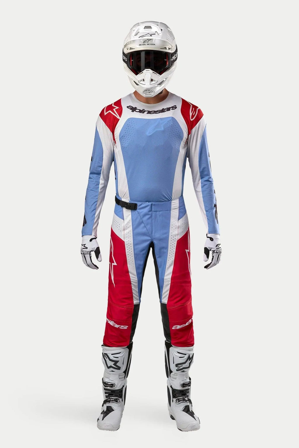 Zawodnik motocrossowy w kompletnym zestawie Alpinestars Techstar Ocuri 2024, jasnoniebiesko-czerwono-biała koszulka i spodnie, biały kask, białe buty i rękawice, profesjonalna odzież wyścigowa do motocrossu