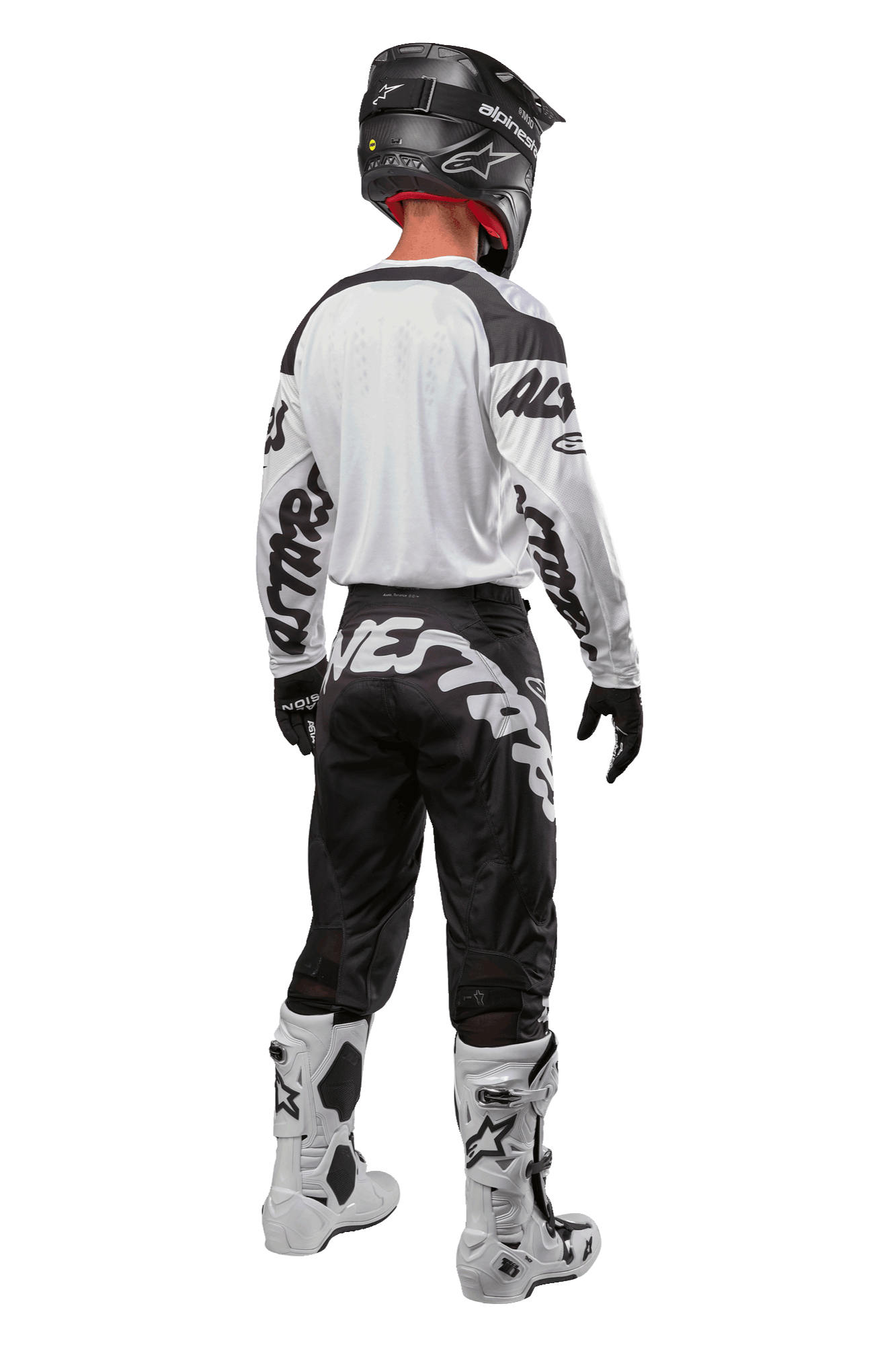 Alpinestars 2024 Racer Hana Jersey, widok z tyłu na zawodnika motocrossowego, biało-czarna, biała koszulka z czarnymi grafikami na rękawach, czarne spodnie z białym napisem Alpinestars na siedzeniu, czarny kask oraz biało-czarne buty, dopasowany strój do wyścigów terenowych