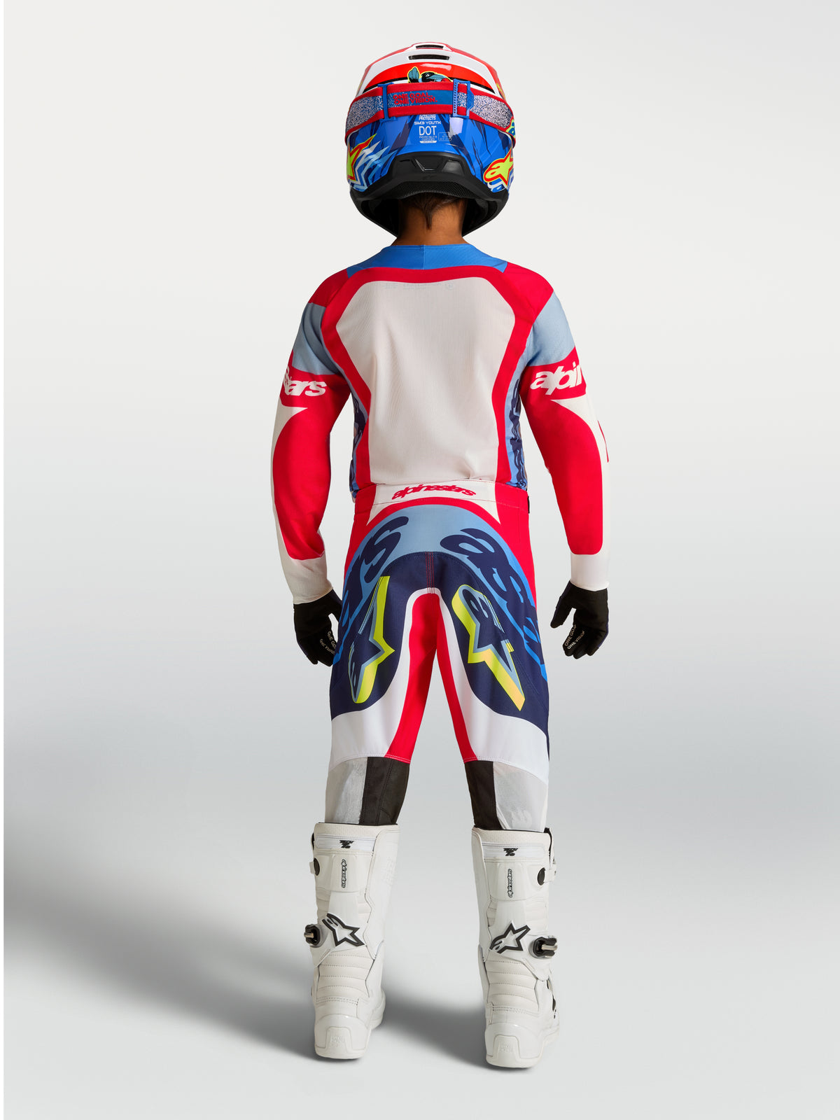 Alpinestars Youth Supertech Dyna, koszulka i zestaw MX, czerwony i niebieski, widok z tyłu na młodym zawodniku.