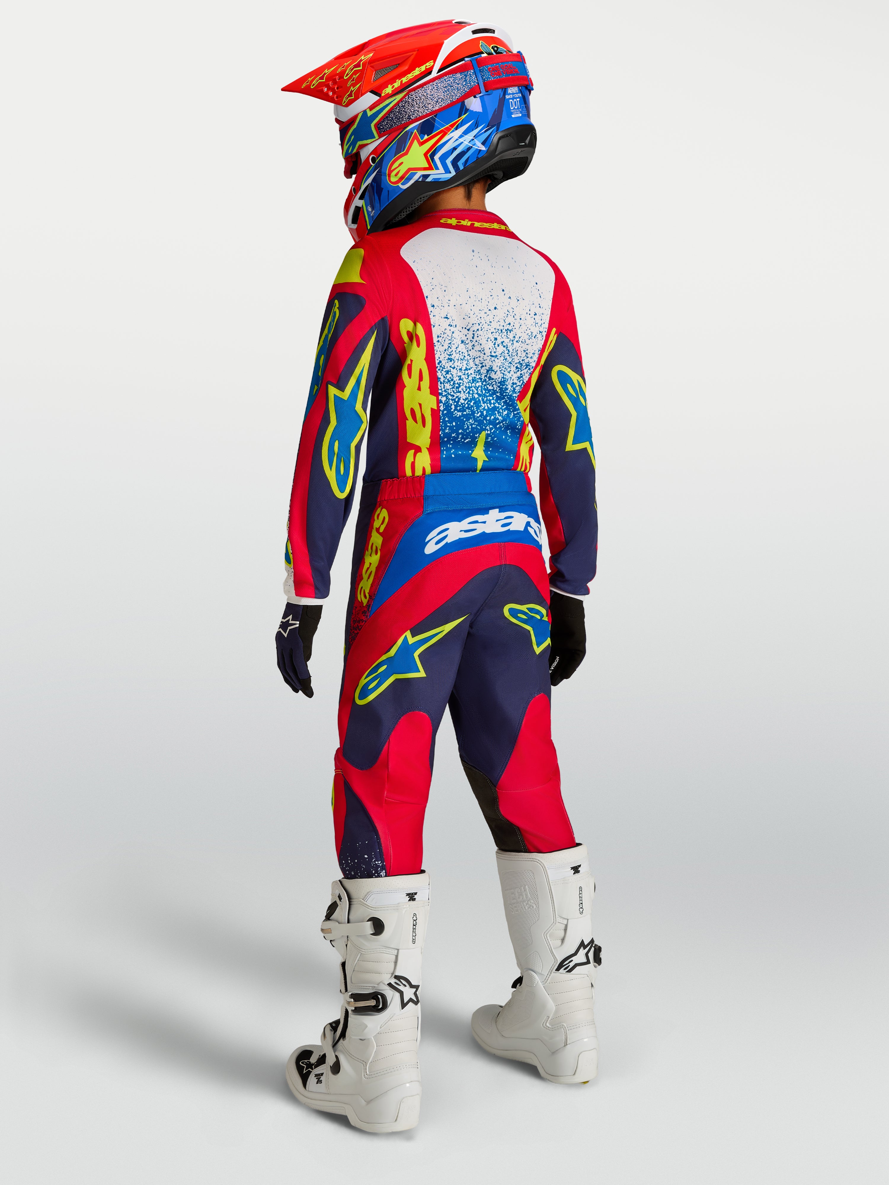 Alpinestars 2027 Youth Fluid Drag, granatowo-czerwony młodzieżowy zestaw motocrossowy, widok z tyłu, białe buty.