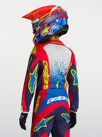 Alpinestars koszulka Fluid Drag młodzieżowa 2027, czerwona i granatowa koszulka motocrossowa z żółtą grafiką, widok z tyłu na zawodniku w kasku, oddychający materiał.