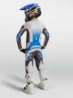Alpinestars młodzieżowe Fluid Drag, szary i niebieski zestaw motocrossowy, widok z tyłu na młodym motocykliście.