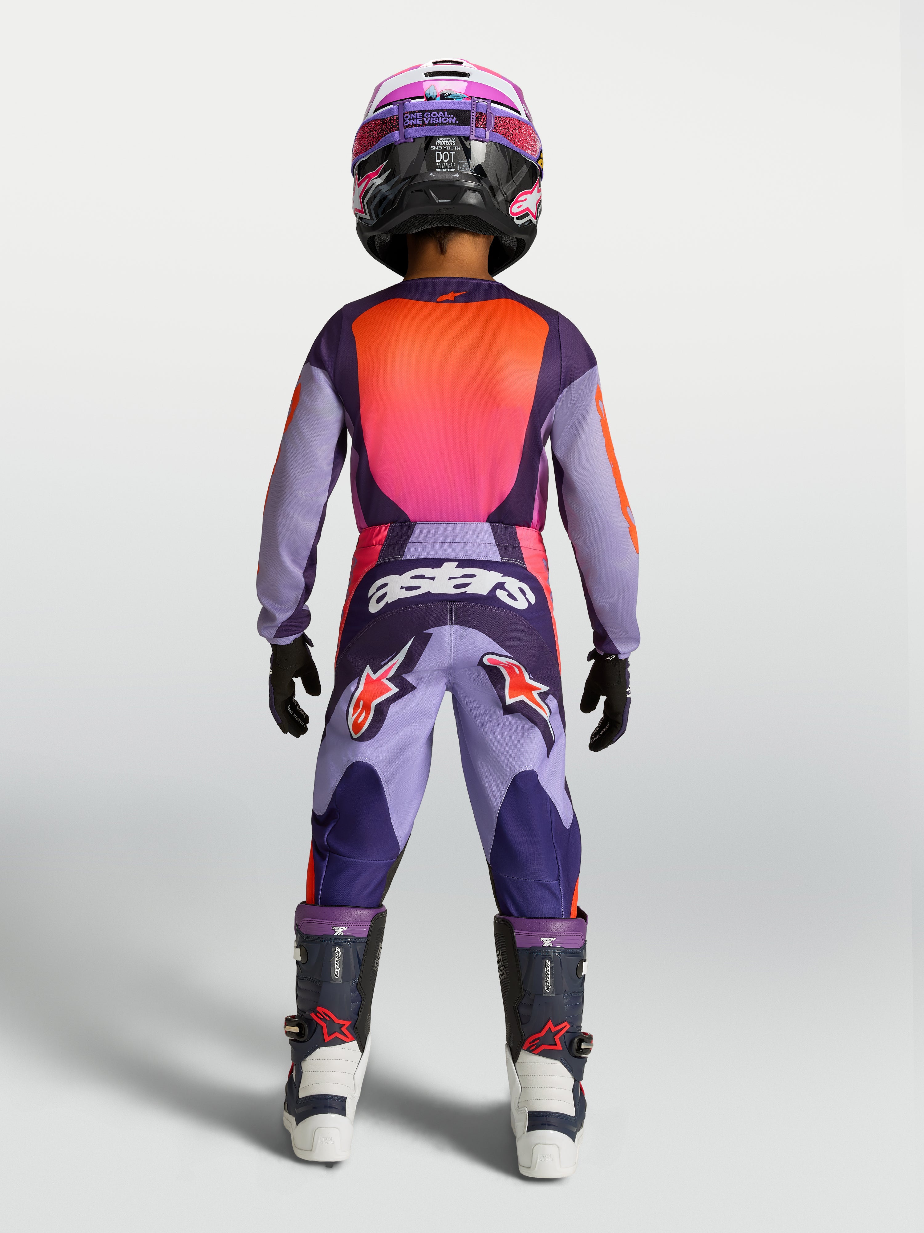 Alpinestars 2027 młodzieżowy zestaw i koszulka Fluid Hunt, fioletowy i różowy fluo strój MX, widok od tyłu na zawodnika.
