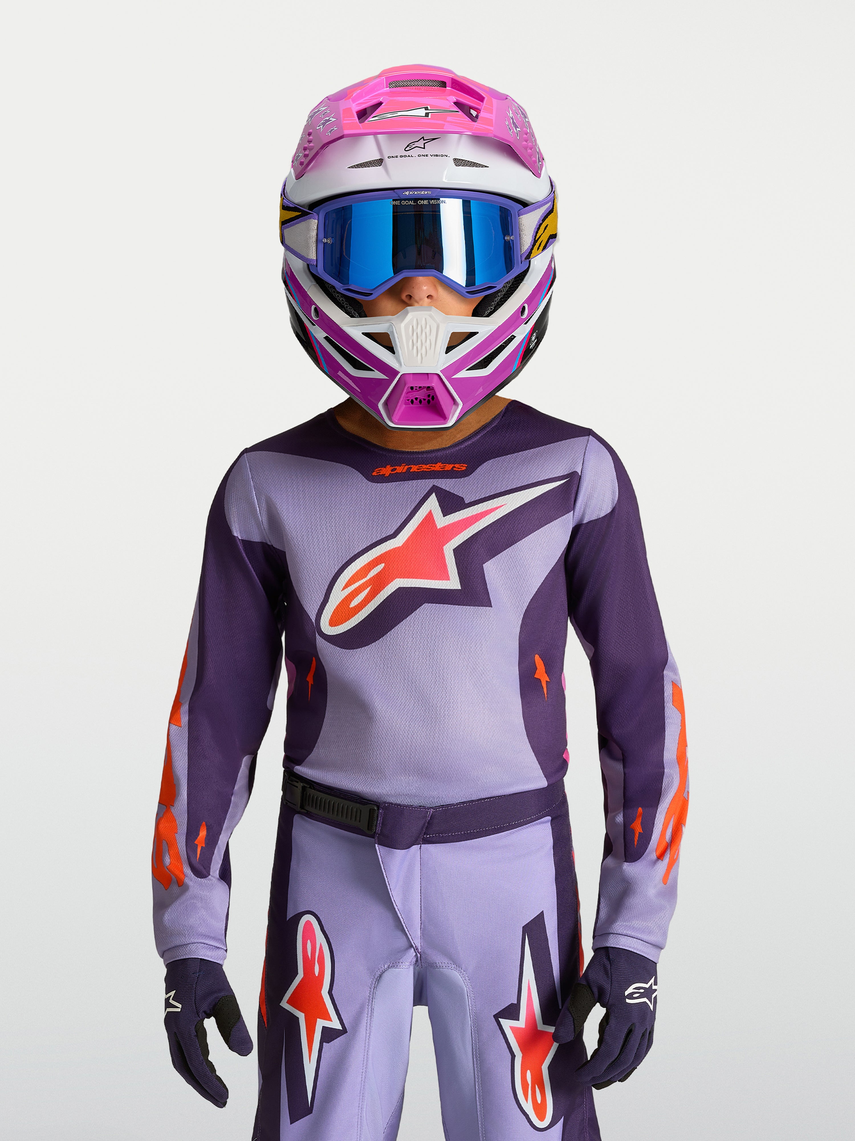Alpinestars koszulka Fluid Hunt młodzieżowa 2027, fioletowa i różowa, na modelu z kaskiem i goglami, profesjonalna odzież motocrossowa