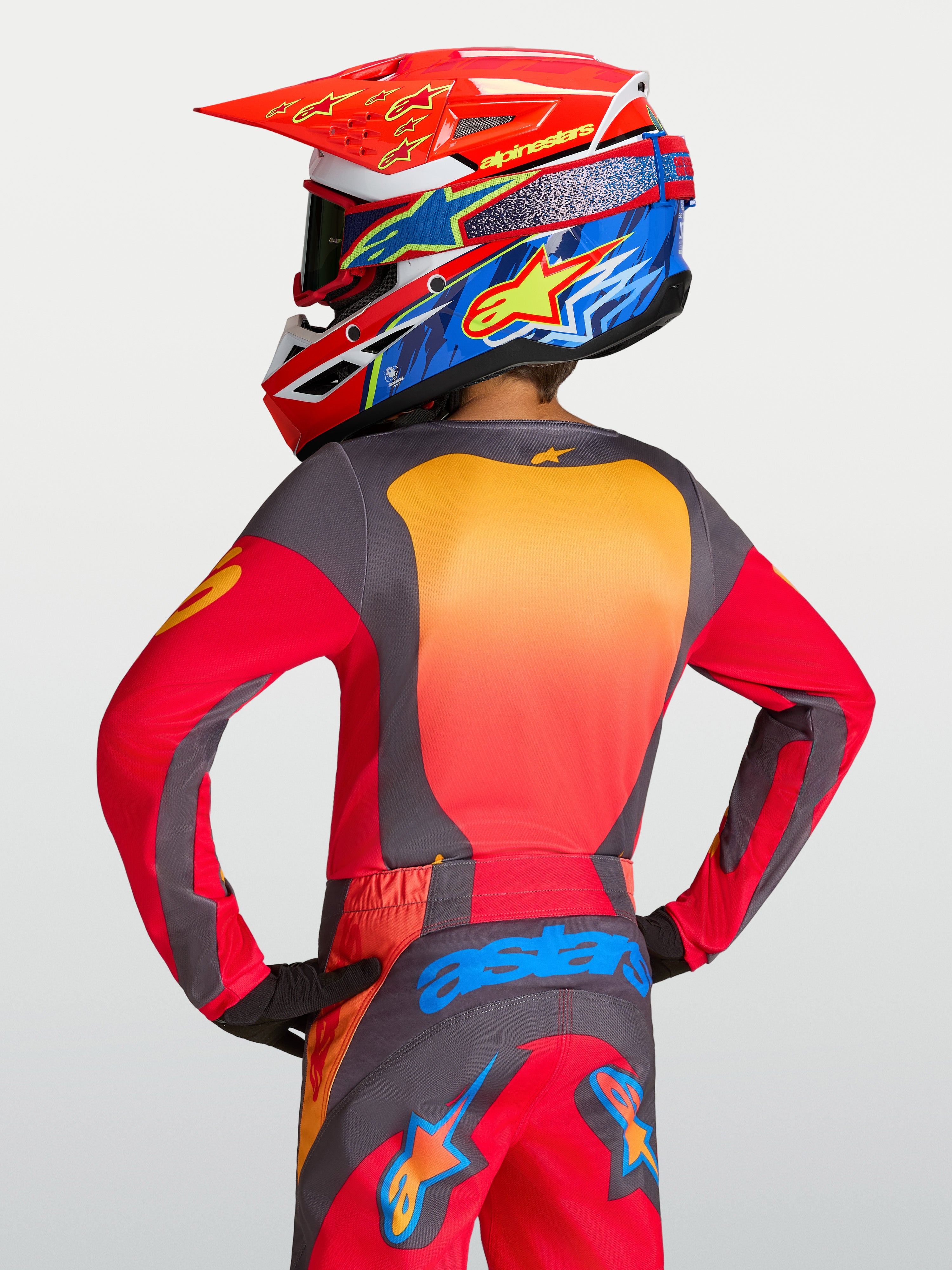 Młodzieżowa koszulka Alpinestars Youth Fluid Hunt, czerwona i szara, sportowy krój motocrossowy, widok od tyłu na modelu.