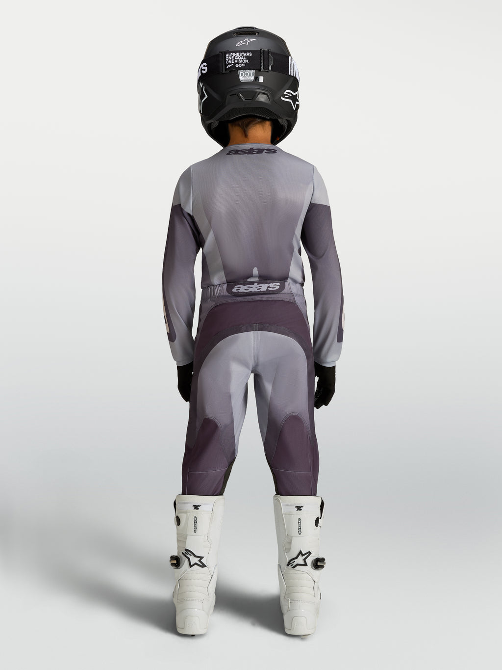Alpinestars Koszulka i zestaw Fluid Amber Młodzieżowe 2027, szary i fioletowy strój motocrossowy, widok z tyłu na zawodnika.