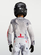 Alpinestars koszulka Fluid Lone Młodzieżowe 2027, szary kamuflaż, widok od tyłu, czerwone akcenty i czarny kask.