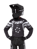Alpinestars Youth 2024 Racer Hana Jersey, młodzieżowa koszulka motocrossowa, czarna z białymi grafikami "Astars" i "Alpinestars", centralny logotyp, model w czarnym kasku, goglach i rękawicach