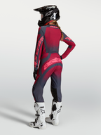 Alpinestars Stella Techstar Swan, damskie spodnie motocrossowe, czerwone i szare, elastyczna konstrukcja stretch, modelka w kasku i białych butach Tech 10, widok z tyłu