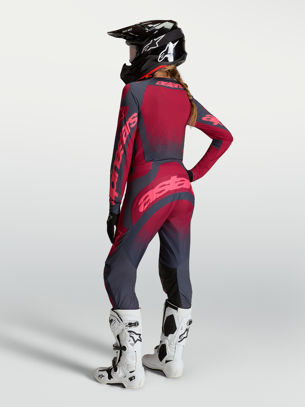 Alpinestars Koszulka Stella Techstar Swan i Stella Techstar Swan Gear Set, damski zestaw motocrossowy, czerwony i ciemnoszary, widok od tyłu na modelkę w kasku i białych butach.