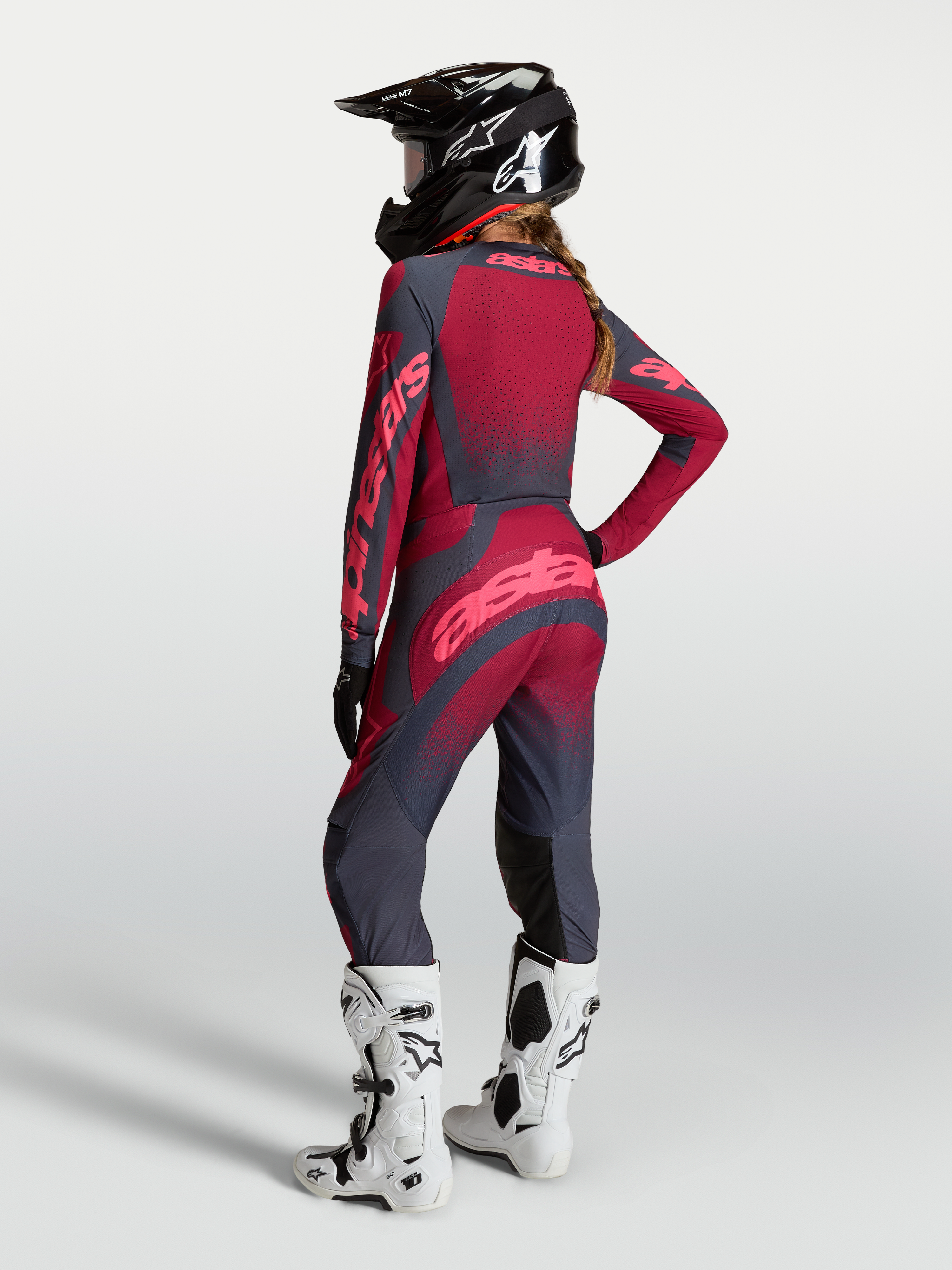Alpinestars Koszulka Stella Techstar Swan i Stella Techstar Swan Gear Set, damski zestaw motocrossowy, czerwony i ciemnoszary, widok od tyłu na modelkę w kasku i białych butach.