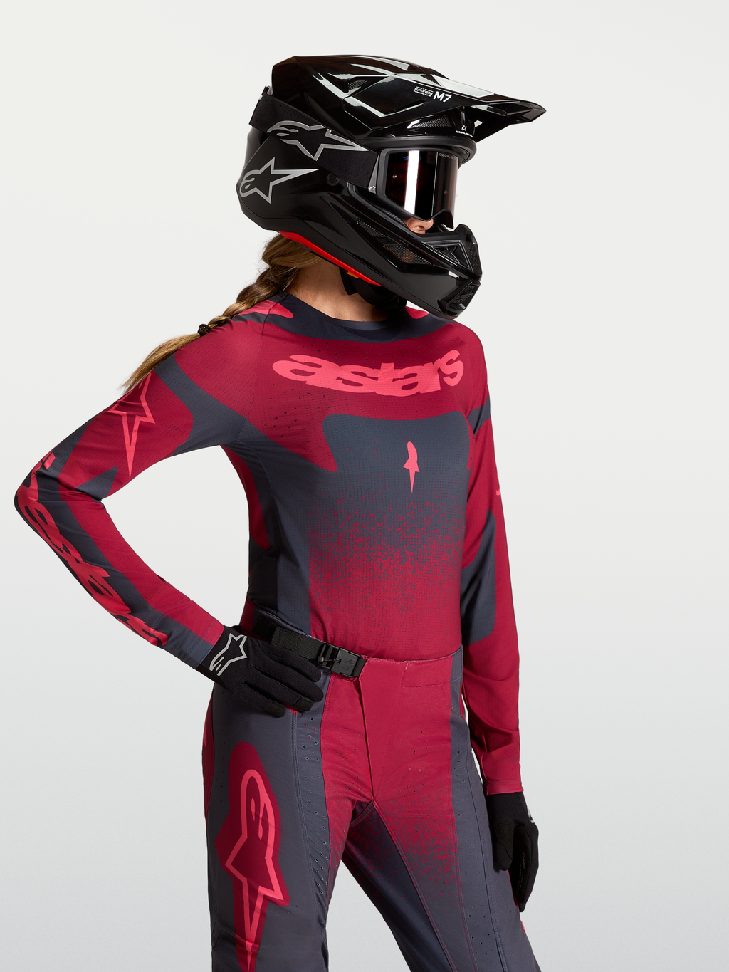 Alpinestars Koszulka Stella Techstar Swan, damska koszulka motocrossowa, ciemnoczerwona i ciemnoszara, sportowy krój wyścigowy, widoczna na modelu z kaskiem i rękawicami MX.