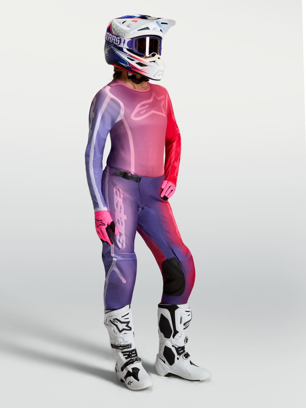 Alpinestars Stella Fluid Kepler, damska koszulka motocrossowa, fioletowa i czerwona, pasujące spodnie oraz białe buty.