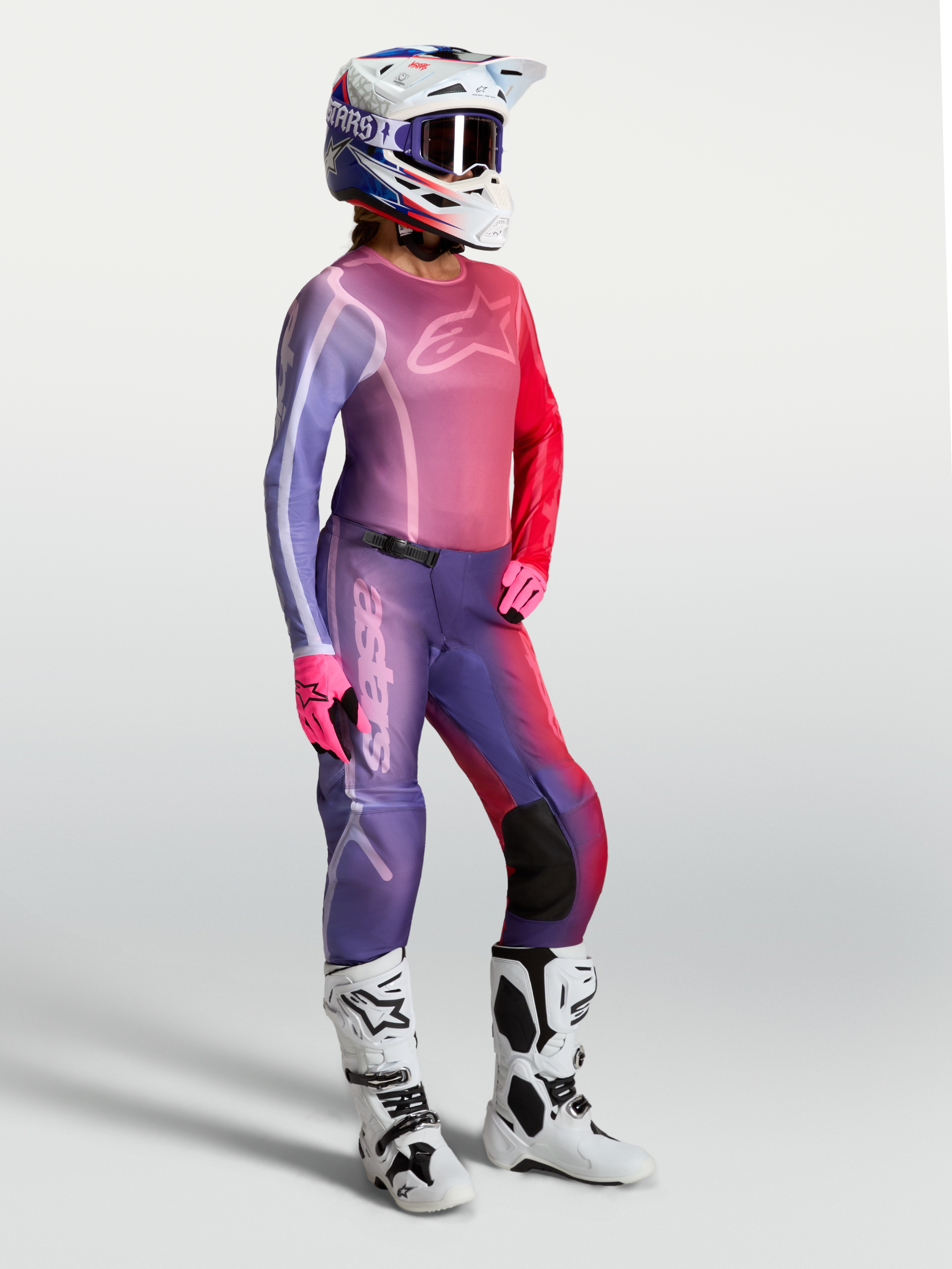 Alpinestars Stella Fluid Kepler, damska koszulka motocrossowa, fioletowa i czerwona, pasujące spodnie oraz białe buty.