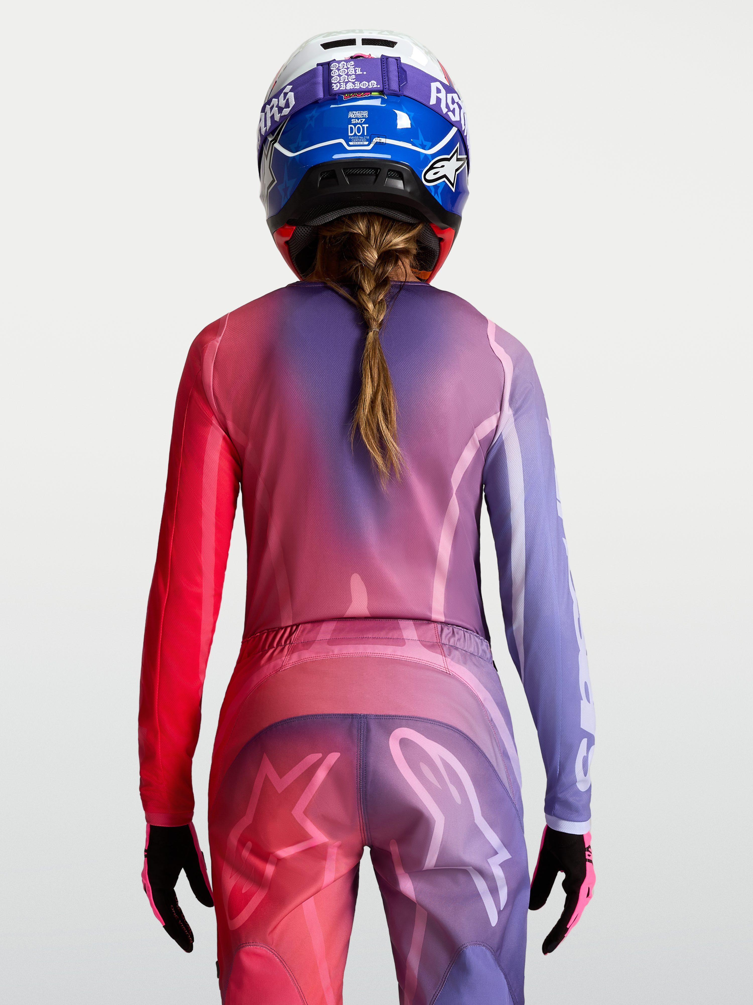 Alpinestars koszulka Stella Fluid Kepler, fioletowa i czerwona damska koszulka motocrossowa, widok z tyłu na modelkę w kasku.