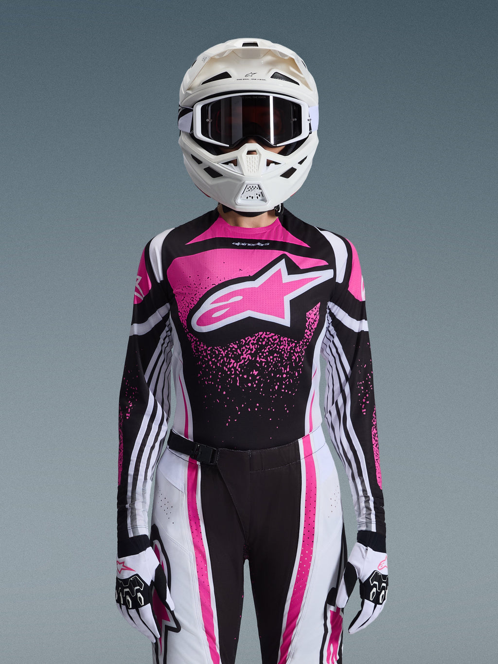 Alpinestars 2026 Stella Techstar Nomur Gear Set, damski strój motocrossowy, różowo-czarno-biały z dużym logo gwiazdy, dopasowana koszulka, spodnie i rękawice, biały kask, widok z przodu na szarym tle