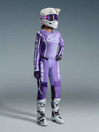 Alpinestars 2026 Stella Fluid Apex Gear Set, fioletowy i lawendowy, motocyklistka motocrossowa w pasującej koszulce i spodniach, biały kask z fioletowymi goglami, biało-czarne buty, czarno-fioletowe rękawice, kompletny strój wyczynowy do kobiecych wyścigów off-road