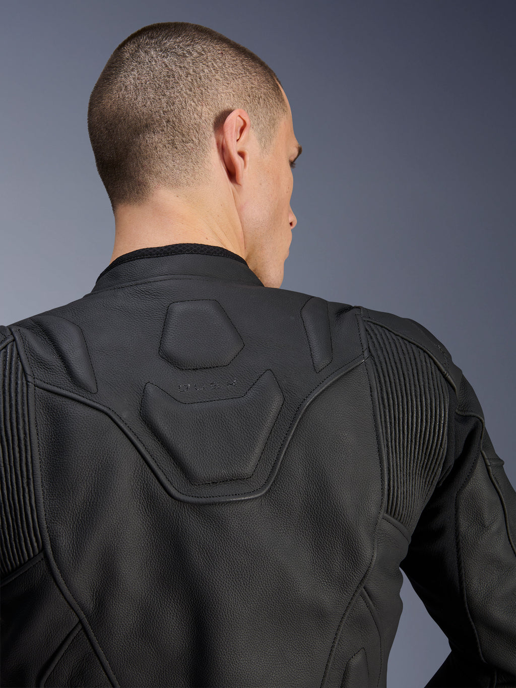 Alpinestars Dusk Leather Jacket, czarna, zbliżenie na górną część pleców i ramiona, wytłoczone logo DUSK na wyściełanym panelu, skórzane elastyczne wstawki akordeonowe, konstrukcja z najwyższej jakości skóry bydlęcej