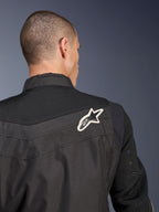 Alpinestars T-Dyno Air Jacket, czarna tekstylna kurtka motocyklowa, zbliżenie na tył podkreślające oddychający karczek i rękawy z siatki 3D, z biało-czarnym logo gwiazdy na prawym ramieniu