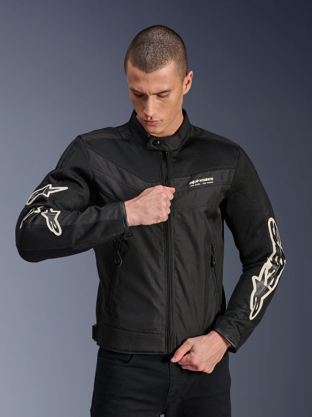 Kurtka Alpinestars T-Dyno Air, czarna, tekstylna kurtka motocyklowa z panelami z siatki 3D i białymi logo na rękawach, noszona przez modela zapinającego zamek, miejski styl jazdy