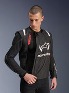 Kurtka motocyklowa Alpinestars T-Stunt Air Jacket, czarno-biała, noszona przez modela, prezentująca modułową konstrukcję z siatki i widoczne wewnętrzne ochraniacze na ramieniu i łokciu, logo Alpinestars na klatce piersiowej, system Tech-Air Ready, sportowy krój do jazdy szosowej