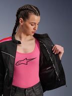 Motocyklistka ubrana w kurtkę Alpinestars Stella T-Dyno Air w kolorze Black Bright Red Fuchsia, częściowo rozpiętą, aby odsłonić wewnętrzną wodoodporną przegrodę, założoną na różowy top z logo, co podkreśla oddychające panele z siatki i dopasowany motocyklowy krój.