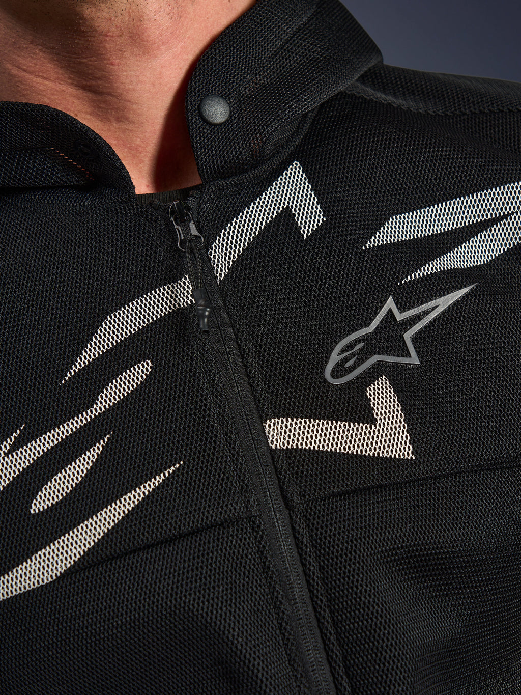 Alpinestars Chrome Superairflow Hoodie, bluza motocyklowa, czarna z biało-szarymi grafikami, zbliżenie na klatkę piersiową pokazujące techniczną konstrukcję z siatki 3D, przedni zamek błyskawiczny i kołnierz zapinany na zatrzask, z logo Alpinestars