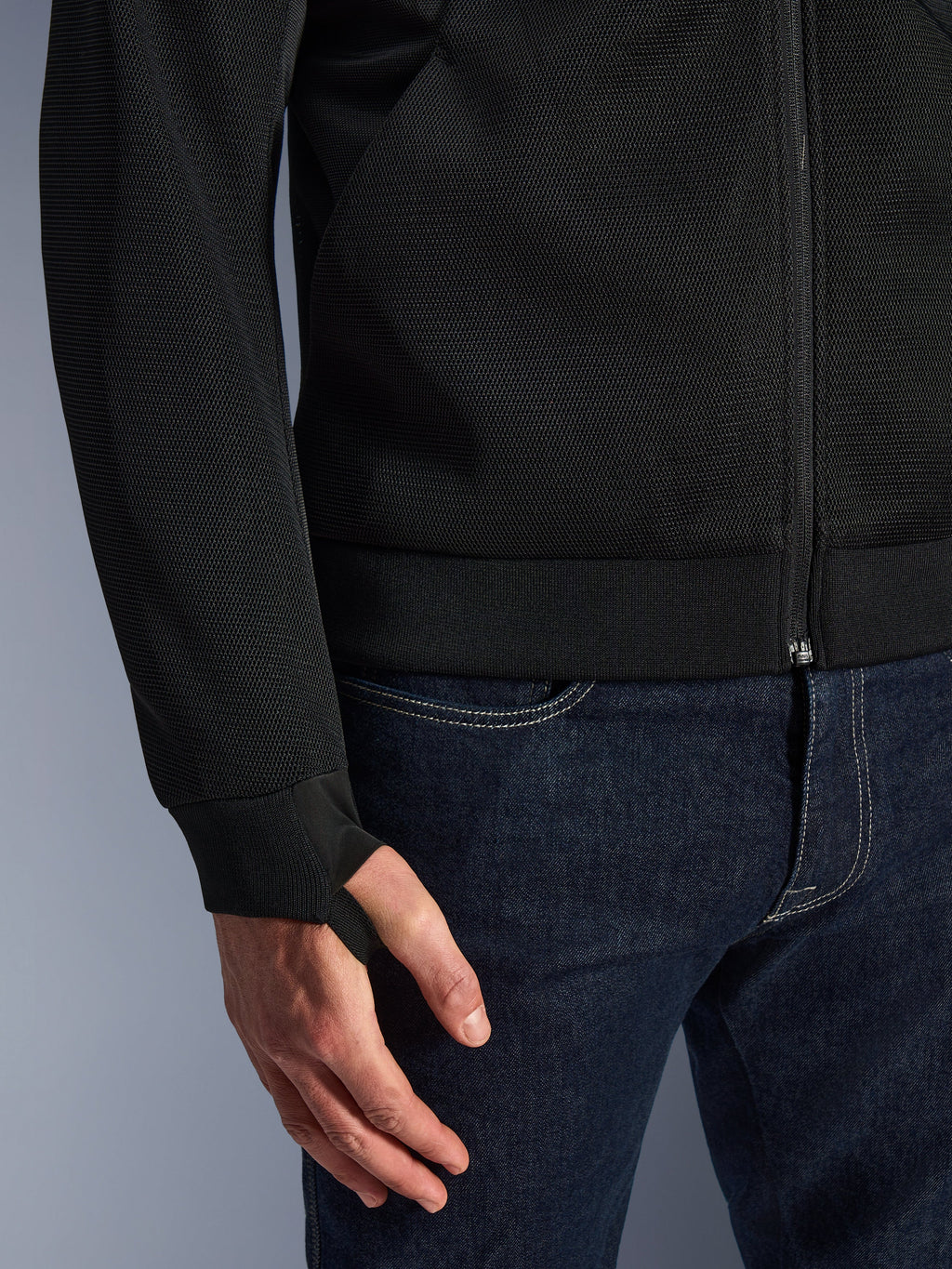 Alpinestars Chrome Superairflow Hoodie, czarna, zbliżenie na wysokoodporną techniczną siatkę 3D, prążkowany elastyczny mankiet z dżerseju z elastyczną pętelką na kciuk, noszona z niebieskimi dżinsami