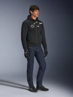 Alpinestars Chrome Superairflow Hoodie, czarna z biało-szarym logo, tekstylna konstrukcja z wentylowanej siatki 3D, zestawiona z ciemnoniebieskimi jeansami i czarnymi rękawicami motocyklowymi, miejski sportowy styl jazdy.