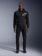 Alpinestars Chrome V2 Sport Hoodie, czarno-biała bluza motocyklowa z dużym białym logo Alpinestars na piersi, zapięcie na zamek i kaptur, prezentowana na modelu w czarnych spodniach i butach, miejska ochronna odzież motocyklowa.