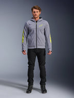 Bluza motocyklowa Alpinestars Chrome V2 Sport Hoodie, szary melanż z jaskrawożółtymi akcentami, miejska odzież motocyklowa, zestawiona z czarnymi spodniami i czarnymi butami motocyklowymi, techniczny polar z wyrazistym żółtym logo na rękawach i klatce piersiowej, swobodny styl miejski