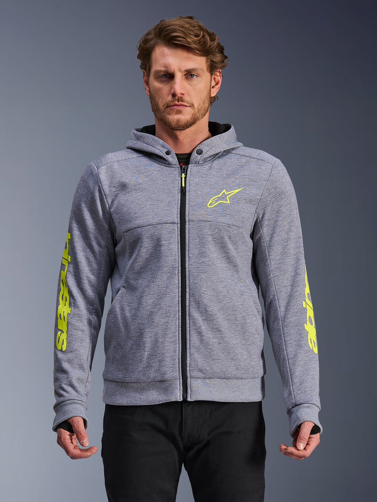 Alpinestars Chrome V2 Sport Hoodie, szary melanż i neonowy żółty, widok z przodu na modelu, techniczna bluza motocyklowa z polaru zapinana na zamek, neonowe żółte logo gwiazdy na piersi i branding na rękawach, codzienna odzież do jazdy miejskiej