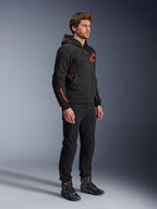 Alpinestars Chrome Air Sport Hoodie, Black Red Fluo, miejska bluza motocyklowa z technicznego polaru, noszona z czarnymi spodniami i butami motocyklowymi, wyposażona w siatkowe panele wentylacyjne i czerwone fluorescencyjne logo na klatce piersiowej i rękawie.